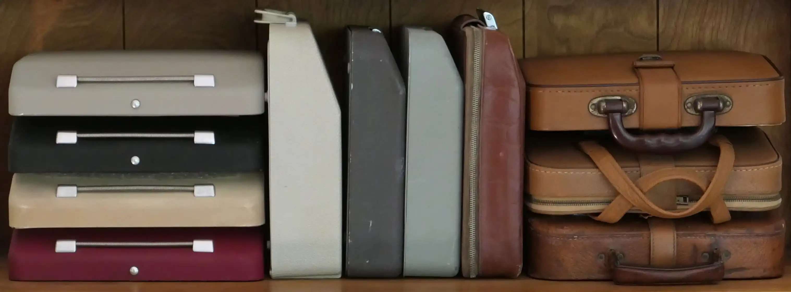 A shelf with eleven ultraportable typewriters in their cases